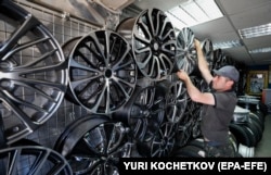 Un comerciant își aranjează marfa la un magazin de piese auto din Moscova, în iunie 2022.