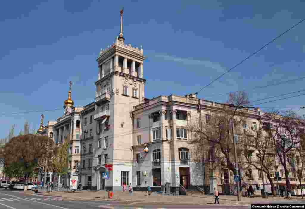 Një nga dy "shtëpitë historike me maja" në qendër të Mariupolit, fotografuar në maj të vitit 2021. / Trupat ruse shihen duke dalë nga një automjet i blinduar pranë "shtëpisë me majë" të epokës staliniste në prill të këtij viti. 