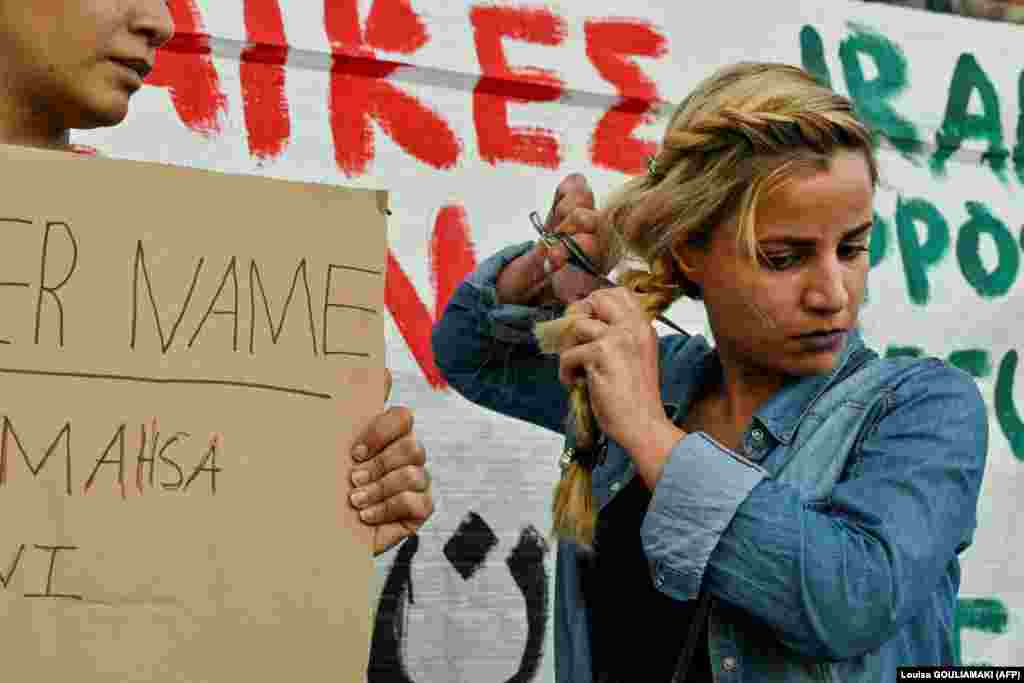 Një grua refugjate iraniane që jeton në Greqi duke prerë flokët gjatë një demonstrate në Athinë, më 24 shtator 2022,