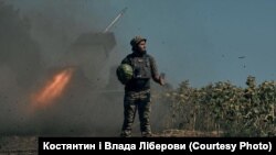 Украински войник държи диня, докато на заден план се вижда стрелящ гранатомет.