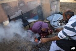 Familja Abu Jarad përgatit çaj në një kamp të improvizuar në zonën Muasi. 1 janar 2024.