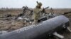 Українські військовослужбовці оглядають уламки збитого російського військового гелікоптера поблизу Макарова, що неподалік Києва, 9 квітня 2022 року