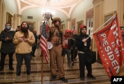 Donald Trump támogatói, köztük közepén a "Q Sámán", a Capitoliumban, miután áttörték a védelmi intézkedéseket és bejutottak az épületbe, 2021. január 6-án.