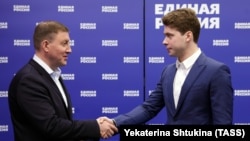Секретарят на Генералния съвет на „Единна Русия“ Андрей Турчак (вляво) връчва членска карта на партията на Иля Медведев, синът на Дмитрий Медведев,