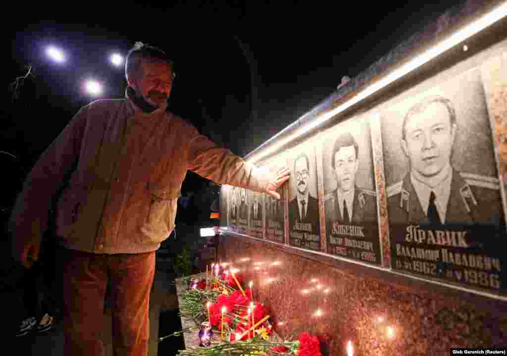 На споменикот во Славутич, еден човек се сеќава на пожарникарите кои загинаа по нуклеарната катастрофа во Чернобил.