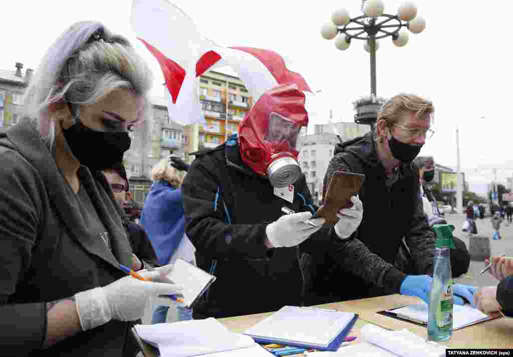 Активисти кои носат заштитни маски и нараквици собираат потписи како поддршка на нивните потенцијални кандидати на претстојните претседателски избори во Минск н