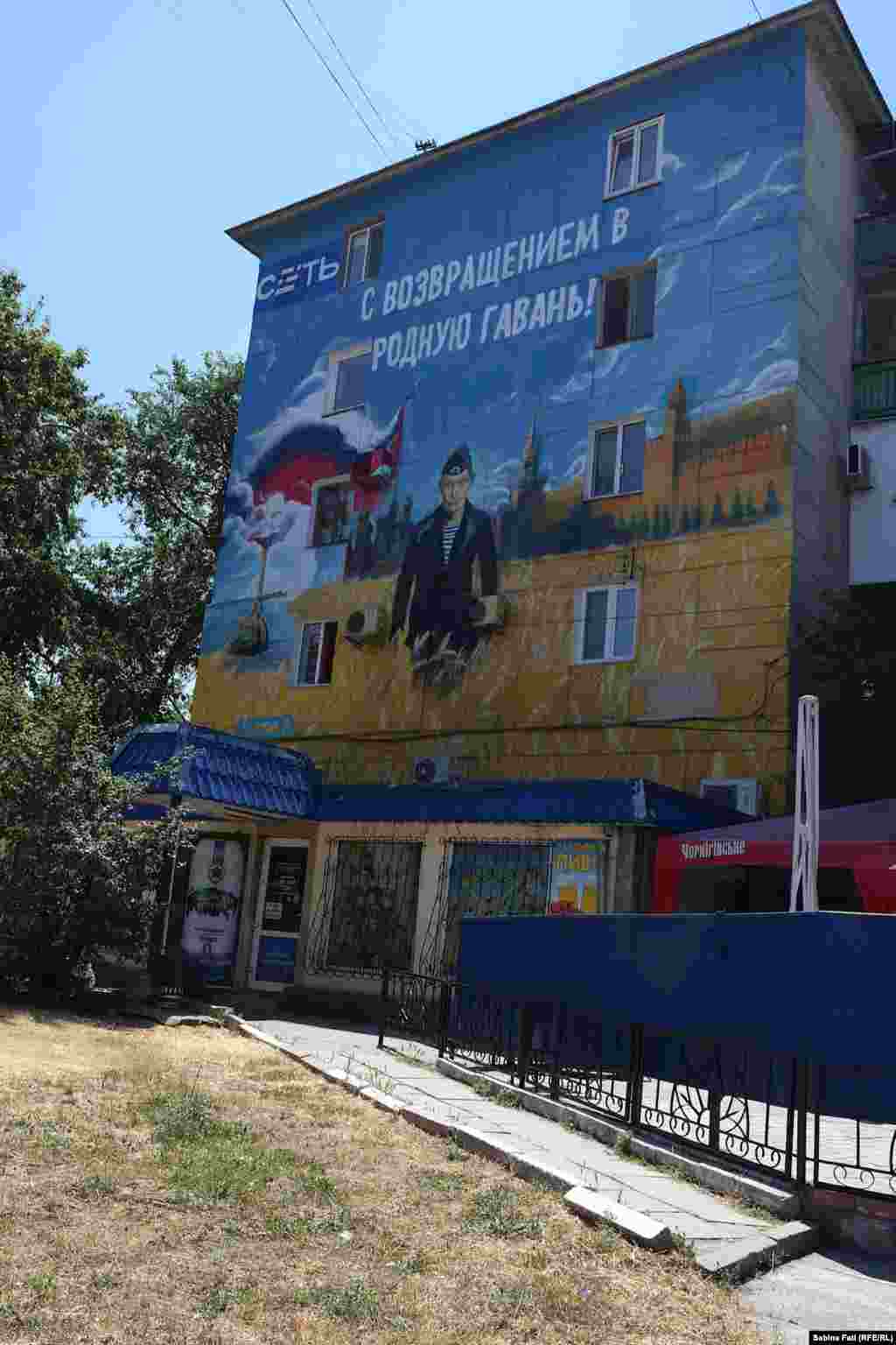 Pictură murală, cu un militar care seamănă cu Putin sub lozinca &bdquo;bine ai revenit acasă&rdquo;
