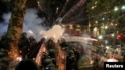 Asemenea imagini se transmit noapte de noapte de la Tbilisi, de peste două săptămâni: protestatarii trag artificii spre forțele de ordine.