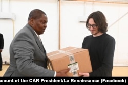 Într-o fotografie postată pe pagina de Facebook a președintelui Republicii Centrafricane, Dmitri Sîtîi (dreapta) apare oferind cutii cu materiale medicale președintelui Faustin-Archange Touadera, în februarie 2025.