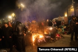 Protestatari lângă o baricadă în flăcări.