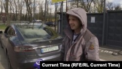 Ukrajinski taksista Anatolij Trepak stoji pored svoje nedavno kupljene Tesle u Kijevu.