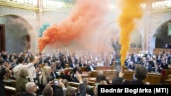 A Momentum képviselői színes füstgyertyákkal a kezükben az Országgyűlés plenáris ülésén 2025. március 18-án