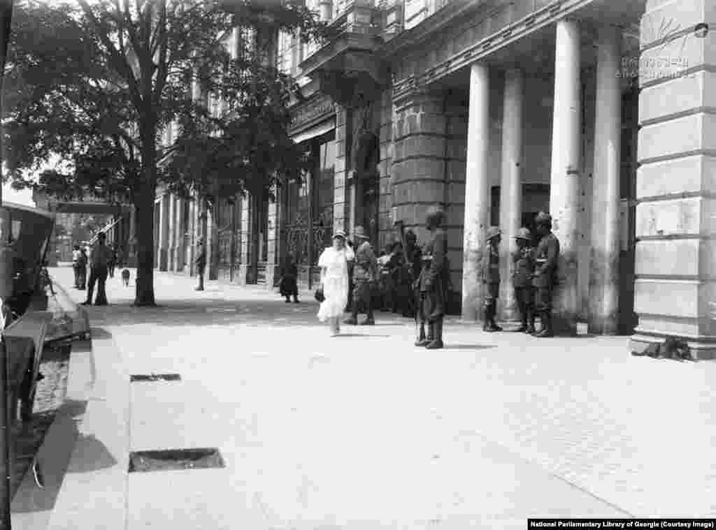 Un trotuar de pe Aleea Rustaveli fotografiat la începutul anilor 1900. Bulevardul a fost numit după Șota Rustaveli, poetul Georgiei din secolul al XII-lea, și era cunoscut pentru hotelurile sale de calitate și trotuarele largi, pe care se putea admira moda zilei. &nbsp;