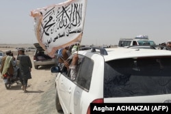 Njerëzit duke valëvitur flamurin e talibanëve teksa kalojnë kufirin me Pakistanin më 14 korrik 2021, pasi talibanët morën kontrollin e qytetit Spin Boldak, që gjendet në pjesën e kufirit të Afganistanit.