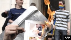 Un protestatar dînd foc unui ziar cu portretul lui Vladimir Voronin în apropierea Parlamentului