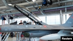 Președintele ucrainean, Volodimir Zelenski (s) și prim-ministra daneză, Mette Frederiksen (d), într-un avion F-16 danez de la baza aeriană Skrydstrup din Vojens. Danemarca și Olanda sunt printre țările care au promis asemenea donații. 