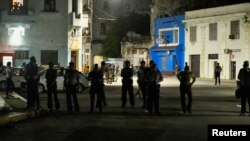 Kubanski policajci stoje na ulici i posmatraju ljude (nisu na fotografiji) koji protestuju jer je njihova ulica ostala bez struje, u Havani, Kuba, 21. oktobra 2024.