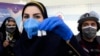 Egy iráni egészségügyi dolgozó az iráni COV Iran Barkat vakcinával egy sajtótájékoztató előtt, amelyen bejelentették a hazai gyártású oltóanyaggal folytatott klinikai kísérletek második és harmadik fázisának kezdetét 2021. március 15-én