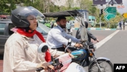 Un bărbat și o femeie merg cu motocicletele în centrul orașului Teheran. (fotografie de arhivă)