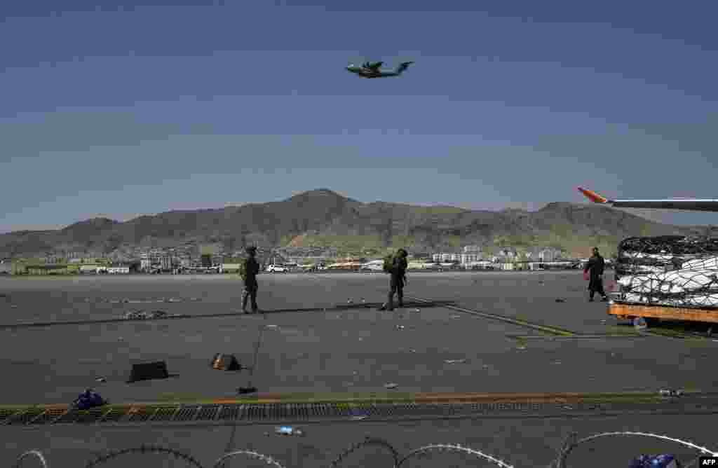 U.S. soldiers stand guard at Kabul airport as a plane takes off on August 16. 