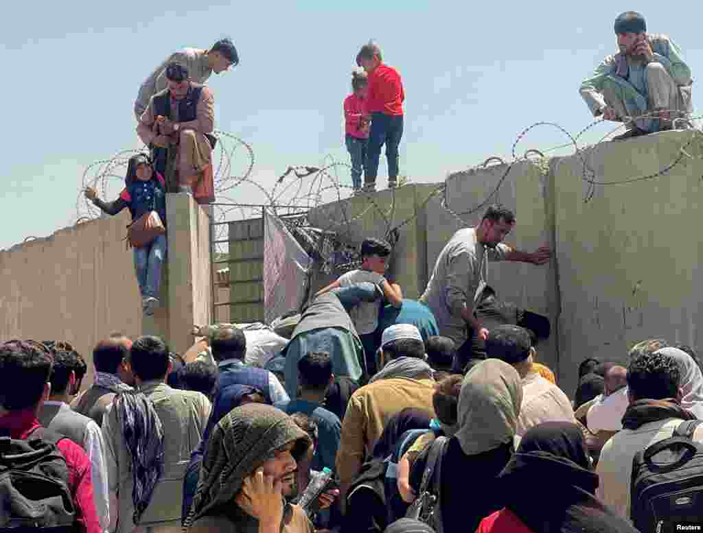 A man pulls a girl over the wall of the airport. 