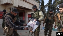 Militanti pale fotografiju sirijskog predsjednika Bašara al-Asada ispred zgrade koju su zauzeli u području Zarbaha 29. novembra 2024.