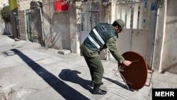 Një polic duke larguar një antenë satelitore në Iran.