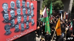 Dhjetëra qytetarë duke ecur pranë një posteri me portretet e shkencëtarëve dhe komandantëve ushtarakë të vrarë gjatë luftës 12-ditore mes Iranit dhe Izraelit, në Teheran.