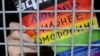 Një aktivist për të drejtat e homoseksualëve e mban një pankartë në dorë me mbishkrimin: "Dashuria është më e fuqishme se homofobia!" teksa qëndron ulur në një automjet policor, pasi ishte arrestuar gjatë një tubimi në qendër të Moskës më 2013.