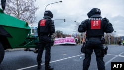Policia e siguron zonën derisa protestuesit e bllokojnë rrugën duke protestuar kundër një konvente të partisë ekstremit të djathtë – Alternativa për Gjermaninë (AfD), në Riesa, Gjermani, 11 janar.
