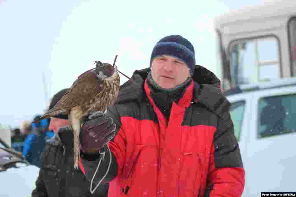 Some Russian falconers visited the tournament, but none was able to compete because of the difficulty involved in transporting birds of prey across borders. Here, a Russian falconer holds a bird belonging to one of the Kazakh competitors. 