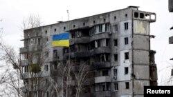 Украински национален флаг пред разрушена жилищна сграда в Бородянка на 18 февруари.