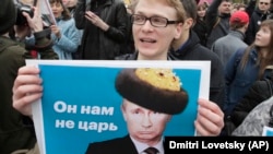 Demonstrantkinja na antirežimskom protestu u Sankt Petersburgu maja 2018., nosi poster sa likom Vladimira Putina i sarkastičnom porukom "On je naš car".