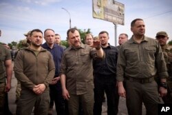 Ukrajinski predsjednik Volodimir Zelenski (lijevo) zahvalio je spasilačkim službama 8. juna tokom obilaska poplavljenih područja u južnoj regiji Herson.