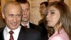 Владимир Путин гледа с усмивка към застаналата до него гимнастичка Алина Кабаева по време на среща с руския олимпийски отбор в Кремъл през ноември 2004 г.