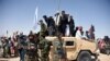 FILE: Afghan Taliban fighters and residents stand on a armored Humvee vehicle of the Afghan National Army (ANA) as they celebrate a ceasefire on the third day of Eid in Maiwand district of Kandahar Province in June 2018.