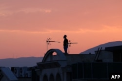 16 iunie 2025 - Un bărbat stă pe acoperișul unei clădiri în timp ce privește orizontul în Teheran. Radiodifuzorul de stat iranian a fost scos pentru scurt timp din emisie de un atac israelian, iar în Teheran s-au auzit explozii.