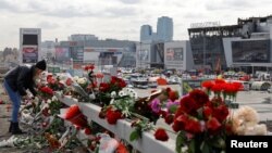 Жена полага цветя на пътя пред зала "Крокус сити хол" след смъртоносната атака, при която загинаха 140 души.