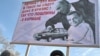 Участники акции протеста во Владивостоке держат плакат с карикатурой на Владимира Путина и Дмитрия Медведева, осуждая повышение таможенных пошлин на автомобили.