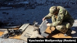 Полицаец проверува фрагменти од дрон Шахед-136 на местото на нападот врз капацитетите за складирање гориво во Харкив на 6 октомври.