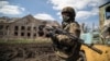Ілюстраційне фото. Український військовослужбовець стоїть біля зруйнованої будівлі в селі Піски, 23 квітня 2015 року