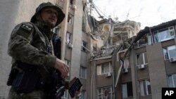 Soldat ucrainean în fața unei clădiri grav avariate de un atac aerian rusesc în Herson, pe 15 iunie. 