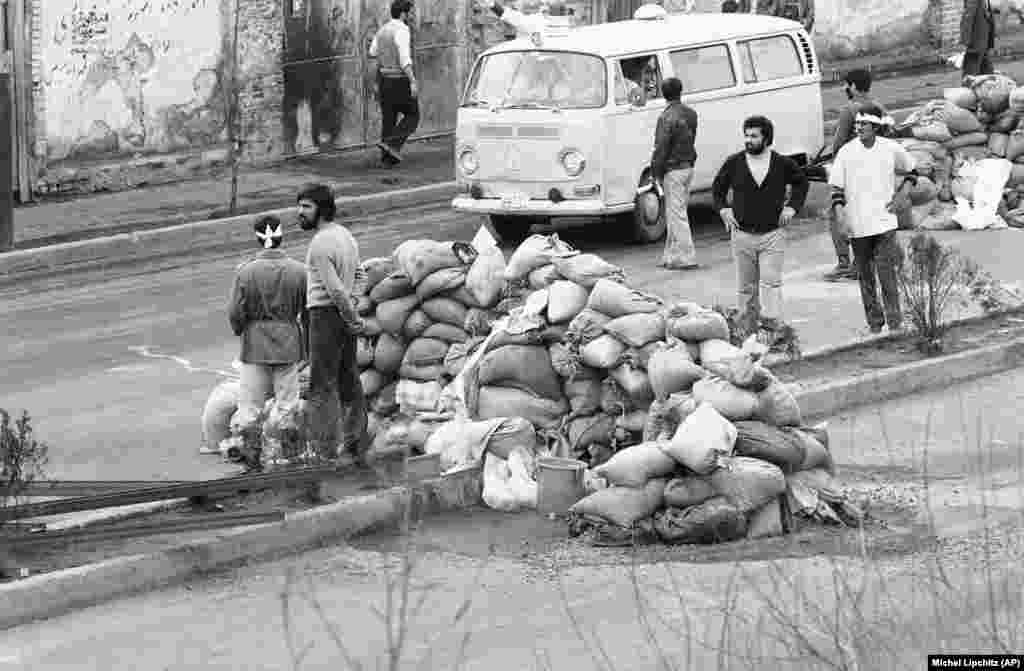 Ambulantna kola prolaze pored barikade od vreća s pjeskom kako bi pokupila ranjene ljude na ulicama nastradalim u nemirima od 10. februara, 1979. U pucnjavi između vojske, kadeta vazduhoplovstva i Homeinijevih pristalica nastradalo je na stotine ljudi a 60&nbsp;&nbsp;ih je umrlo.&nbsp;&nbsp;