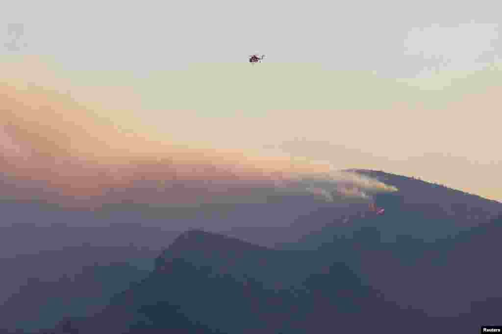 Një helikopter zjarrfikës fluturon mbi një zjarr në ishullin Samos, Greqi, 13 korrik 2022.