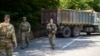 Militari americani din KFOR patrulând lângă un camion sârbesc care bloca șoseaua în apropiere de Zubin Potok, 1 august 2022.