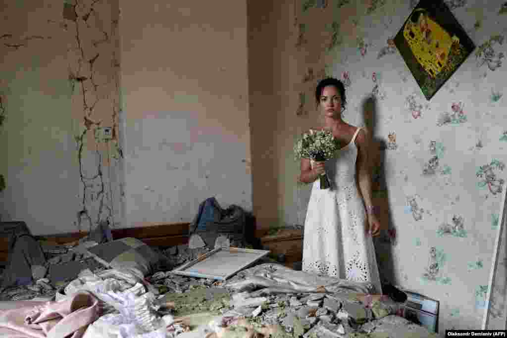 Dariya Steniukova, 31 vjece, pozon për fotot e dasmës në banesën e saj të bombarduar në Vinitsja më 16 korrik. Një raketë goditi qytetin 200 kilometra në jugperëndim të Kievit, një ditë përpara se të bëhej dasma e Steniukovas. &ldquo;Shtëpia ime u rrënua, por jo jeta jonë&rdquo;, tha ajo për AFP. &quot;Ishte një mesazh sfidues për të gjithë botën -- duke theksuar se sa të fortë janë ukrainasit. Ne jemi gati të martohemi me gjithë raketat që fluturojnë mbi kokat tona&quot;, tha ajo.