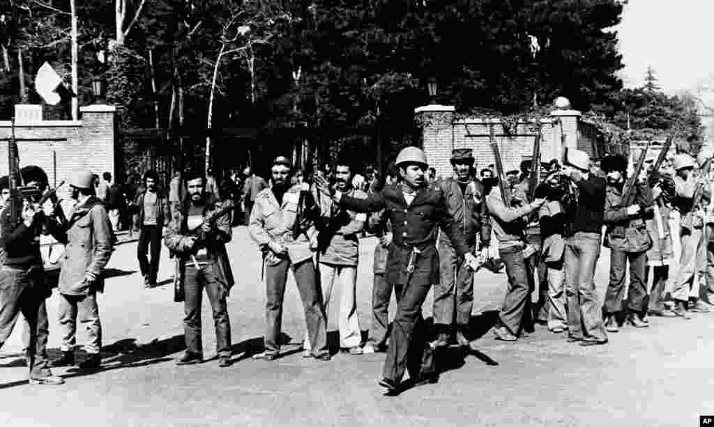 Naoružane pristalice ajatolaha stoje ispred ambasade Sjedinjenih Država u Teheranu 15. februara 1979. godine, dan prije nego što je kompleks bio opustošen. Ambasada je kratkotrajno pala u ruke ajatolahovih pristalica prije nego što je vraćena Sjedinjenim Državama. Drugi poklušaj da se okupira ambasada SAD-a desio se u novembru &ndash; talačka kriza trajala je 444 dana.