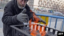 Egy hajléktalan férfi melegszik a begyújtott szén mellett Varsóban 2012. január 31-én 