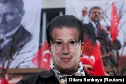 Un protestatar poartă o mască decupată a primarului Istanbulului, Ekrem Imamoglu.