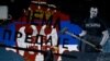 Koszovói szerb asszony sétál el egy graffiti előtt, amelyen a szerb zászló alatt a Nem adjuk fel felirat áll Mitrovica főként szerbek lakta, északi részében. 2021. június 15.